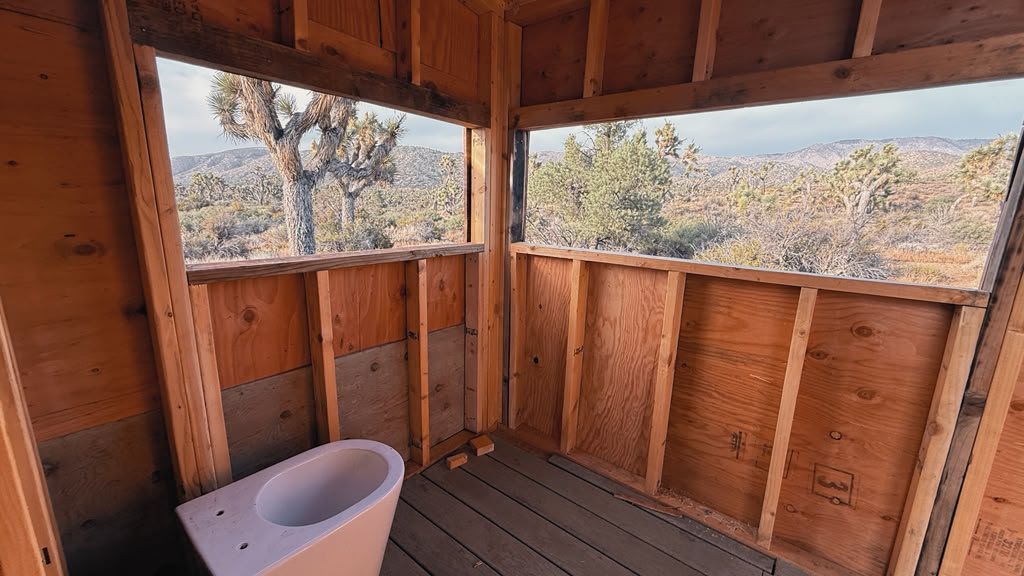The view from the toilet seat: two wide openings frame Joshua trees and desert mountains